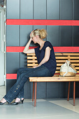 tired woman sits on a bench, propping her head up with her hand
