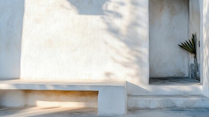 White stucco wall, bench, plant, shadows, steps.