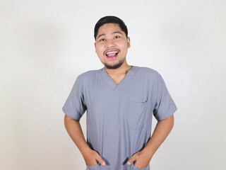 Fototapeta premium Asian male nurse standing and showing excited expression while smiling