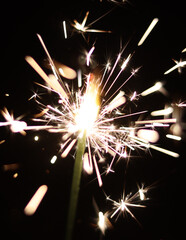 A sparkling sparkler illuminated against a dark backdrop. This image captures the vibrant glow of...