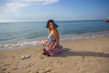 blonde girl, sitting on the shore, on a suitcase, traveler, looking around, long hair, blue hat, summer sundress, sea surf, pleasure boat, sea, sun, summer, ocean, travel, woman, vacation, coast, 