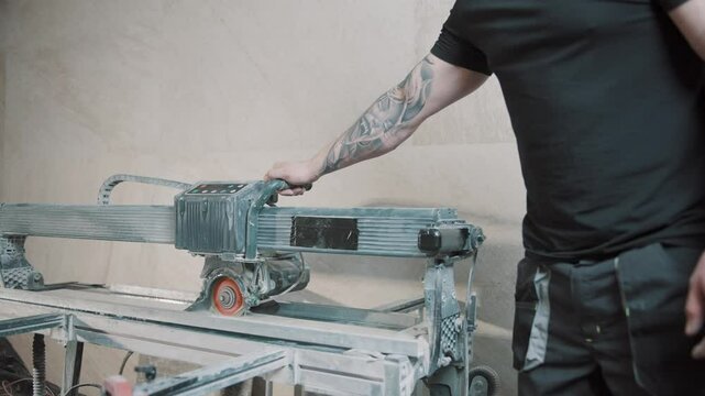 Man using slow motion tile cutting tool in construction project indoors