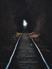 An evocative shot of train tracks vanishing into a mysterious, dimly lit tunnel, creating a sense of anticipation and journey