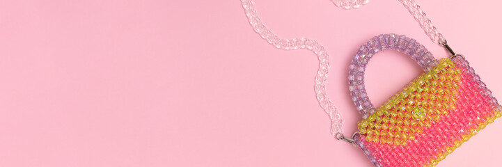 Banner with handbag made from acrylic beads on a pink background. Place for text.