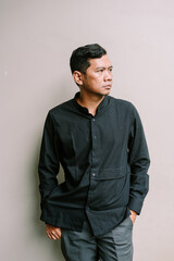 Obraz premium Thoughtful asian man in minimalist style clothing against neutral backdrop
