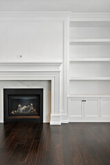 White fireplace with a mantle and a white bookshelf in the background