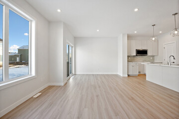 Large, empty living room with a kitchen and a window