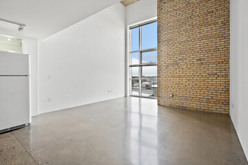 Large empty room with a window and a brick wall