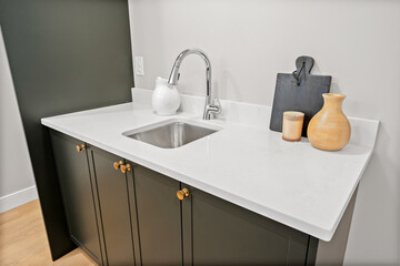 Sink is on a counter with a vase and a cutting board