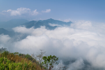 A serene view of the mist-covered mountains in Fanlu Township, Chiayi County, Taiwan, captured on a spring afternoon. The dense fog creates a mystical atmosphere, enveloping the lush green hills.
