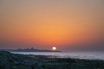 Spring evening scene at Shimen, New Taipei City, Taiwan. Sunset, waves, and a lighthouse view. Detailed landscape shot.