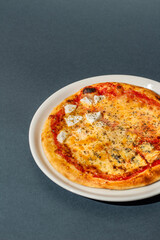 Four cheese pizza, homemade Italian pizza. Pizza on dark gray background. Traditional Italian cuisine. Place for text, top view.