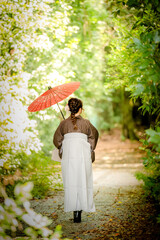A woman in a Hakama kimono holds a Japanese traditional umbrella walking on the street. Kyoto,...