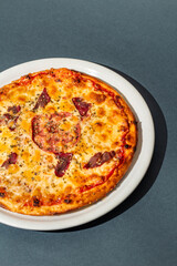 Pizza with mozzarella cheese, ham and sauce on plain grey background