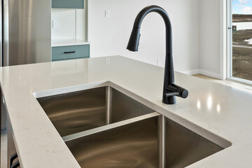 Stainless steel sink with a black faucet sits on a white countertop