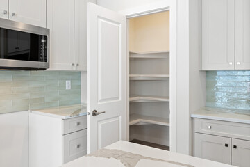 Fototapeta premium White kitchen with a white door leading to a white pantry