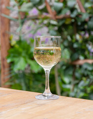 Glass of wine on a wooden table outdoors.