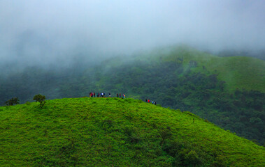 A group of toursits enjoying the view from top of a hill in Chikmagalur - on the way to Baba Budan Giri hills (Karnataka, India)