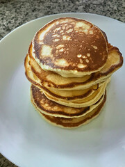 Stack of pancakes on white plate at the table