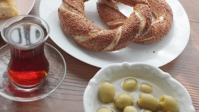 Local Turkish breakfast table Turkish tea, su boregi, green olives and simit bagel	
