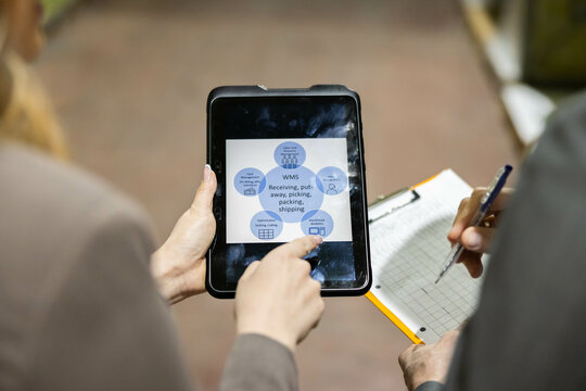 A team member illustrates a digital interface while collaborating on inventory management insights in a warehouse setting.