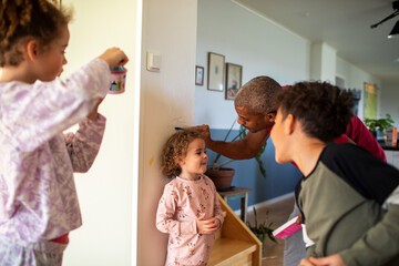 Father measuring his kids height on wall at home