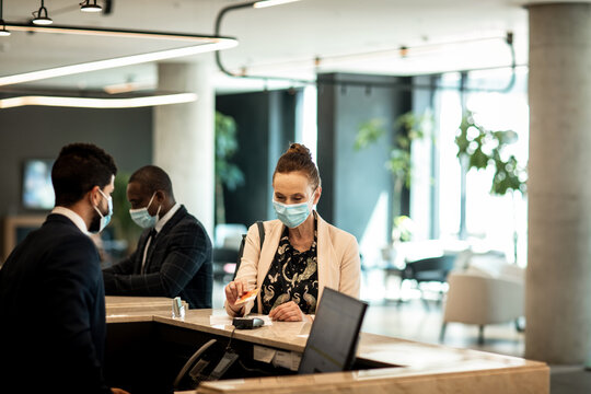 Businesswoman paying at hotel check in during pandemic safety protocols