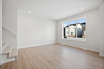 Large, empty living room with a window and a staircase