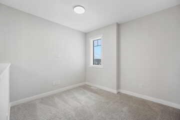 Small, empty room with a window and a white wall