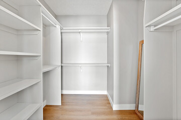 White closet with a mirror and a wooden floor
