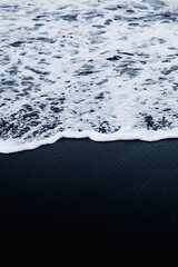 Waves break softly over black sand in a striking seascape from Vestrahorn, southeast Iceland..