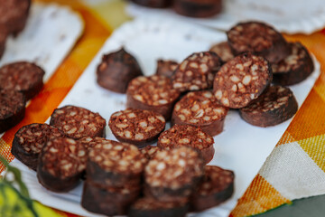 Close-up of blood sausages with grains in a coiled arrangement inside a woven basket, showcasing their dark, glossy texture and traditional preparation style.