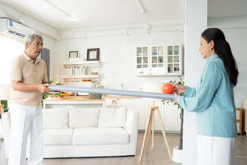 Asian senior couple playing rolling ball for practice balance and concentrate in the living room at...