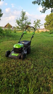 Moscow obl., Russia - June 29, 2024:Electric lawn mower Greenworks on lush green grass in sunny garden scene
