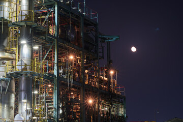 Industrial Refinery Structure at Night with Moon in the Sky