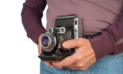 Vintage camera held by person outdoors in casual attire showcasing love for photography