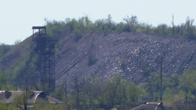 Industrial scene with shimmering heat haze above a mine headframe and spoil tips. Environmental impact of mining. Sunny hot weather, air shimmer. Climate change and global warming concept video
