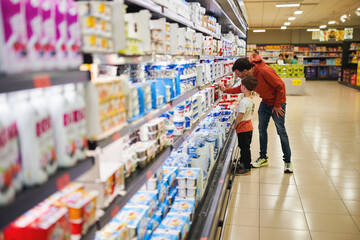 Father and son shopping in dairy section of supermarket