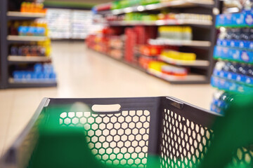Shopping basket in grocery store aisle with blurred shelves