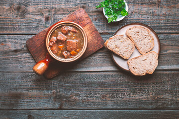 Meat goulash with vegetables on a wooden background.