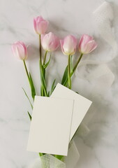 Greeting cards mockup and pink tulip flowers on white marble background top view flatlay. Blank mock up with copy space.