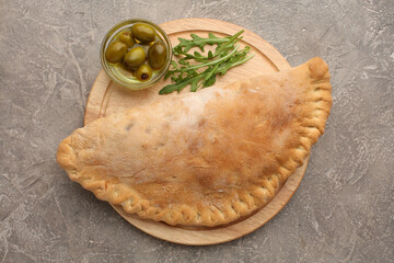 Pizza calzone with basil leaves close up with restaurant background. classic italian food