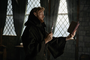Medieval priest holding cross and holy bible performing exorcism rite