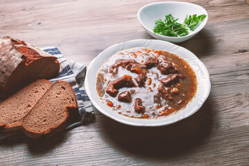 Meat goulash with vegetables on a wooden background.