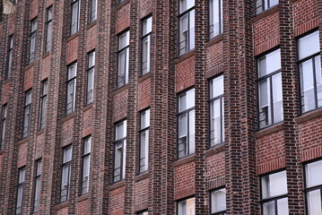 A building with a repetitive facade of red brick and evenly spaced windows. The image shows a tall urban structure.