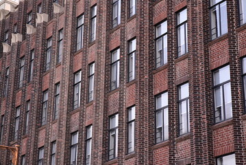 A building with a repetitive facade of red brick and evenly spaced windows. The image shows a tall urban structure.