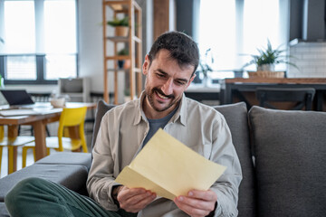 Happy man reading good news in a letter at home