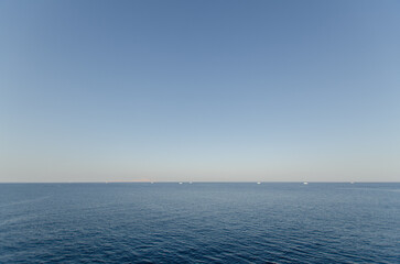 Vast ocean view meets light blue sky at serene resort. Calm waters create tranquil ambiance. Horizon appears endless, evoking sense of peace and freedom