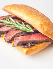Grilled ciabatta sandwich with melted cheese, juicy steak, caramelized onions, and rosemary