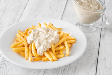 Golden fries drizzled with rich blue cheese sauce on white plate